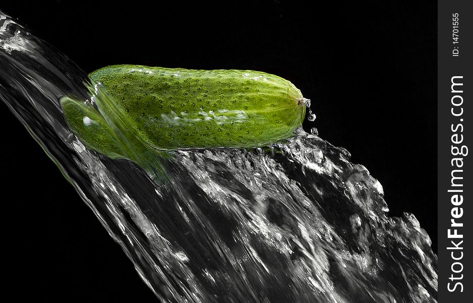 Cucumber passing through the water on a black background