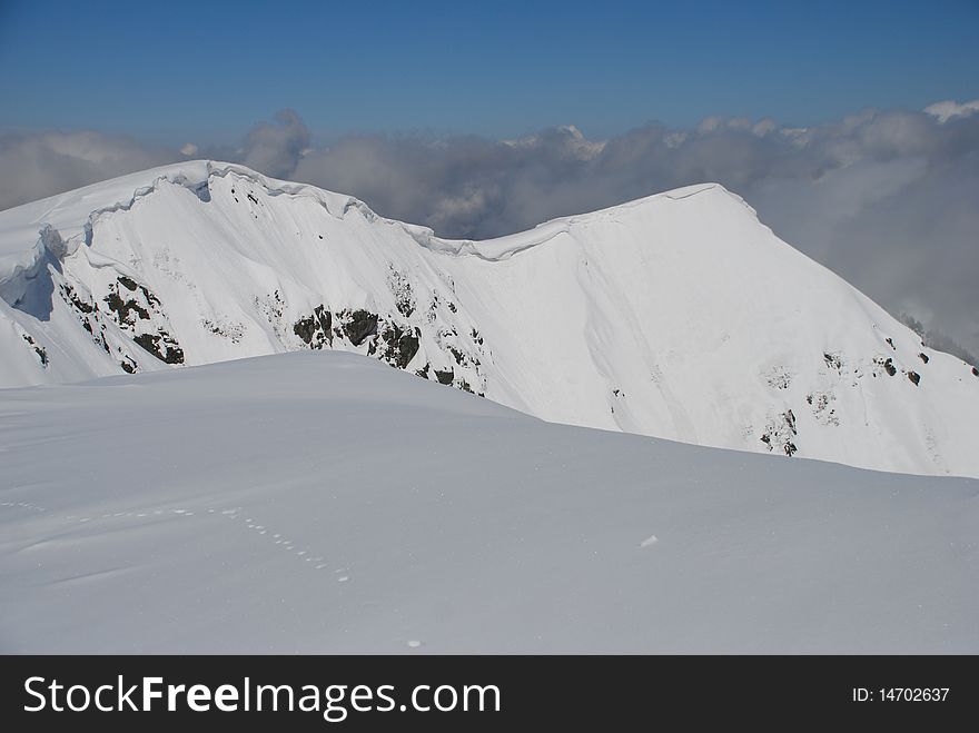 A mountain winter slope in clouds in a landscape with white snow. A mountain winter slope in clouds in a landscape with white snow.
