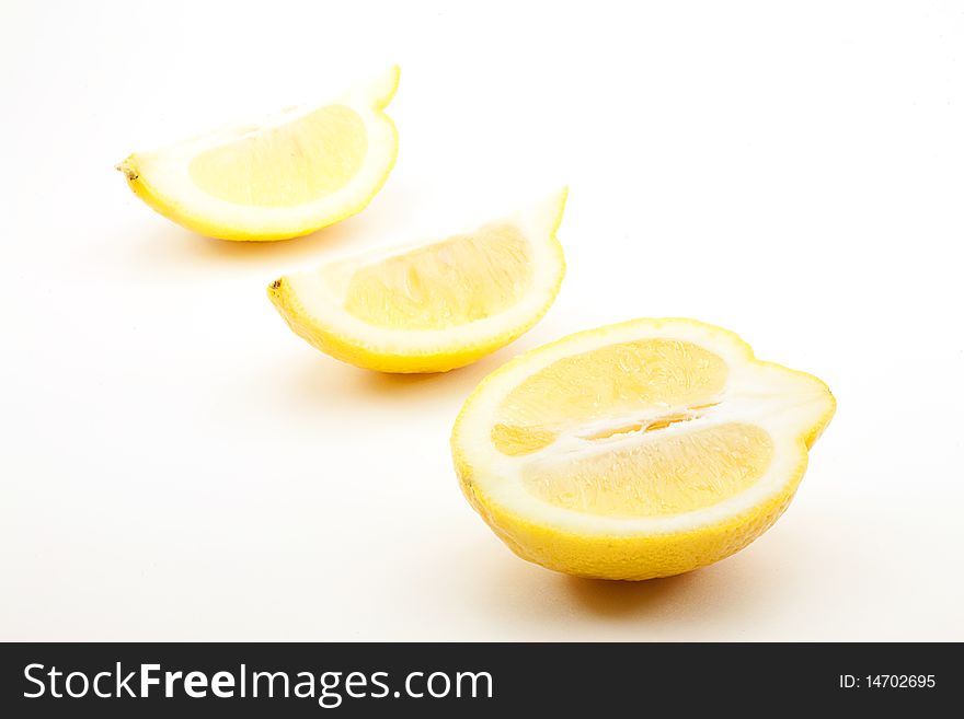 One half lemon and two lemon sections on white background. One half lemon and two lemon sections on white background.