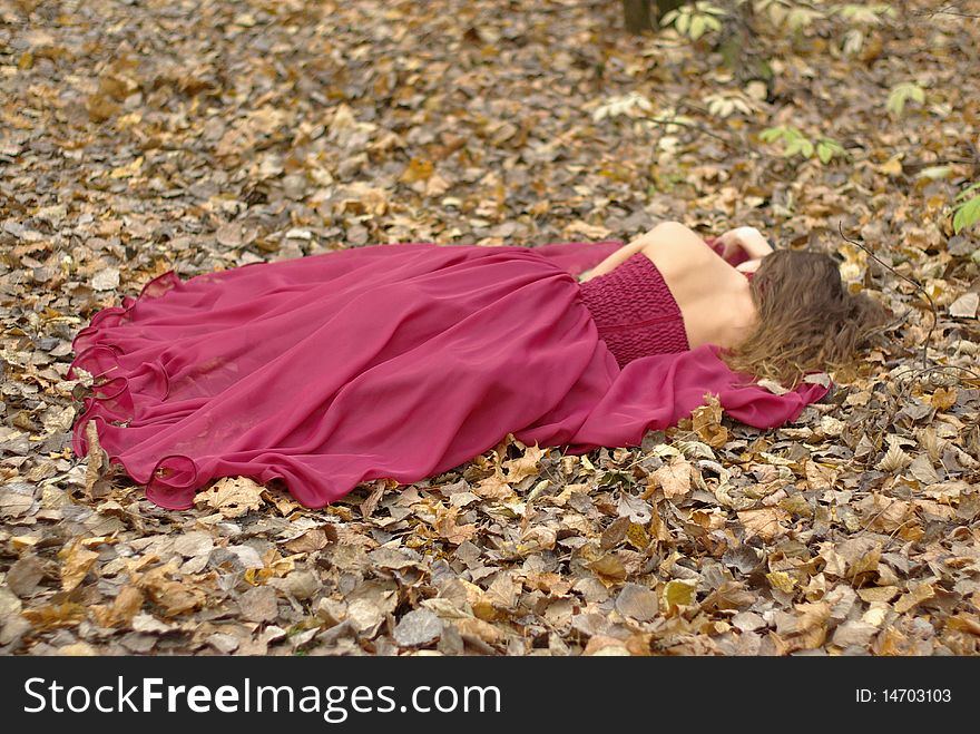 A girl in a red dress lying on the fallen leaves. A girl in a red dress lying on the fallen leaves