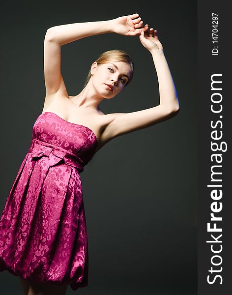 Beautiful young woman wearing pink dress on a dark background