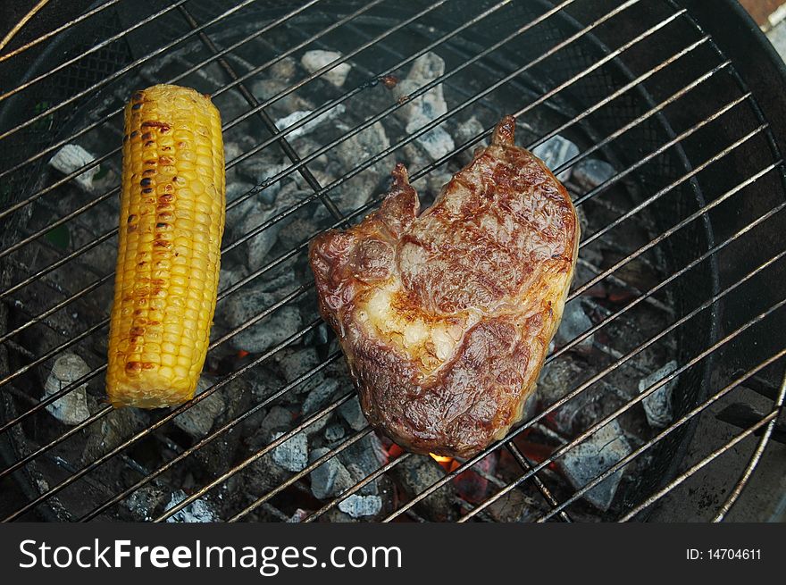 Ribeye steak and corn on a charcoal grill. Ribeye steak and corn on a charcoal grill