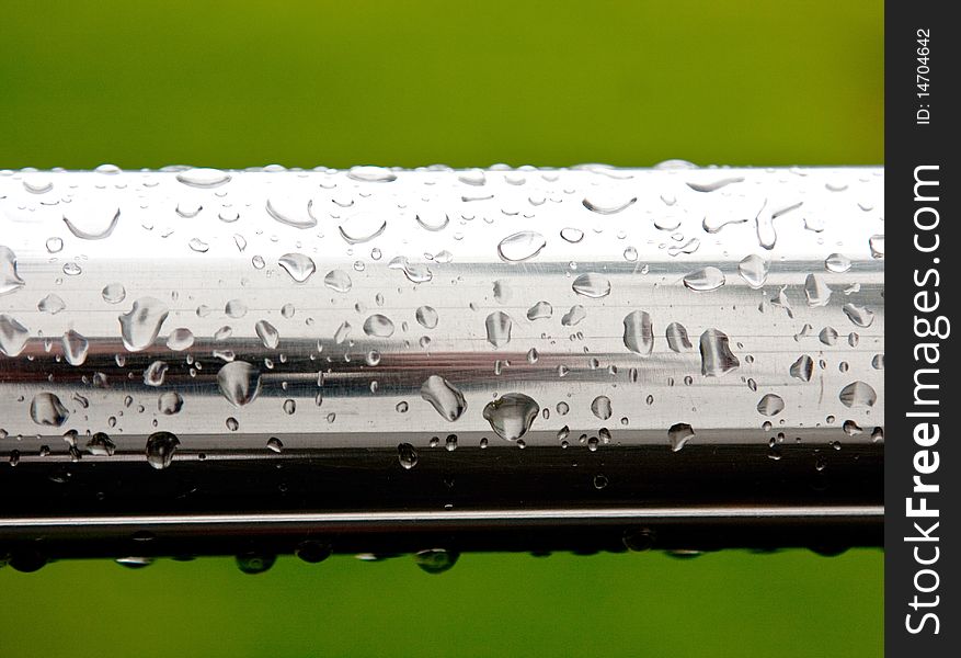 Rain drops on chrome surface on green background