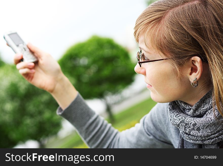 The young girl holds a mobile phone in hands