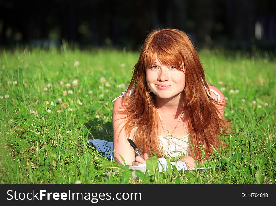 The girl smiles, in the grass at summer. The girl smiles, in the grass at summer