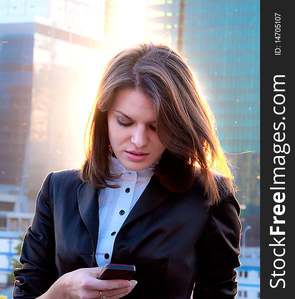 Young business lady writing sms in the big city background