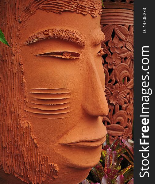 Strict looking orange colored terracotta face