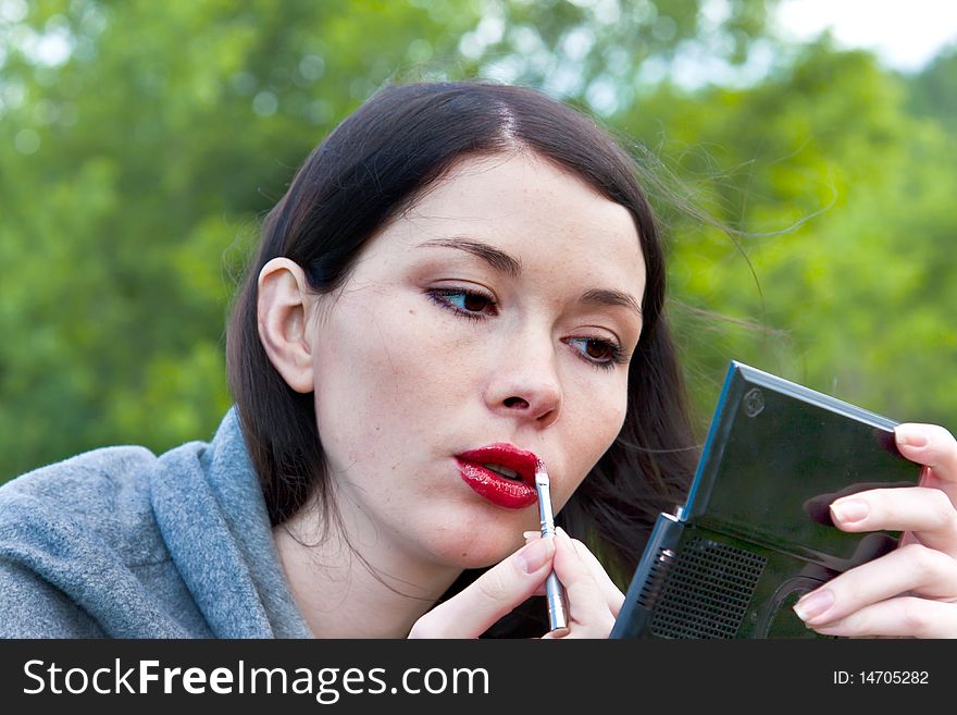 Cute lady performing makeup outdoors