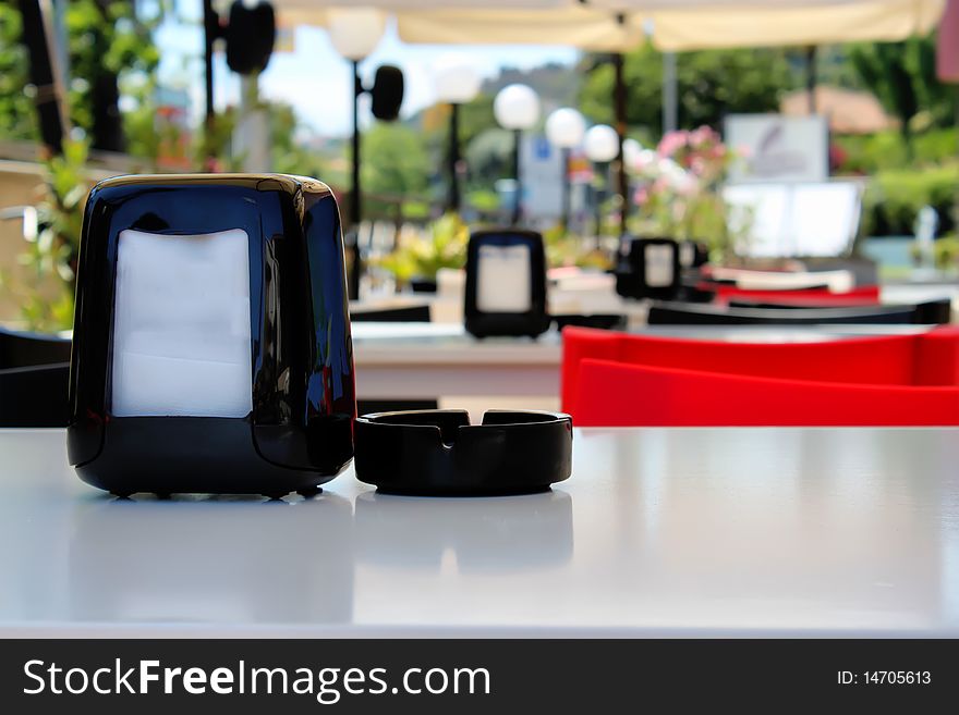 Photo of napkin and black ashtray on the table in bar on open air. Photo of napkin and black ashtray on the table in bar on open air