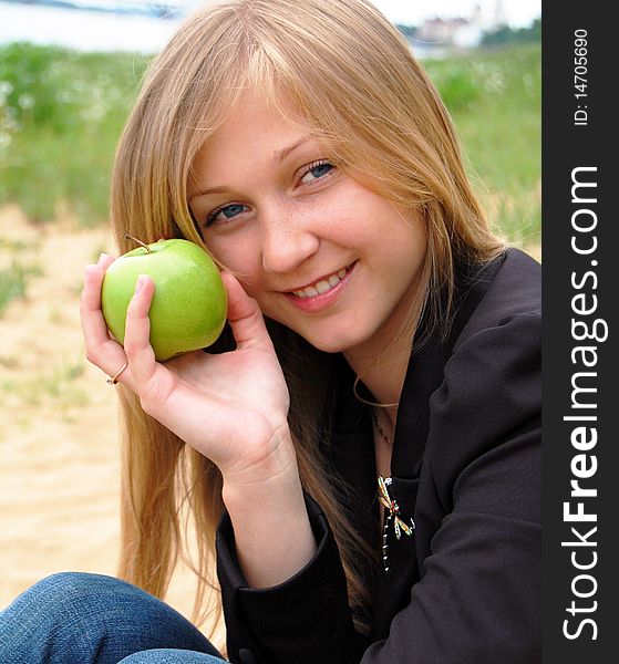 Beautiful young woman with green, big apple, smiling and looking in camera. Beautiful young woman with green, big apple, smiling and looking in camera