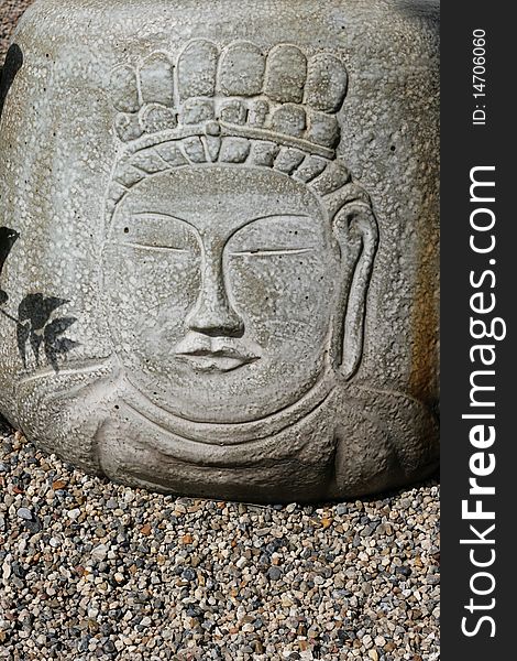 Buddha's face has been carved onto stone. It's simple in design, Zen style and is placed in a Japanse styled garden. Buddha's face has been carved onto stone. It's simple in design, Zen style and is placed in a Japanse styled garden.