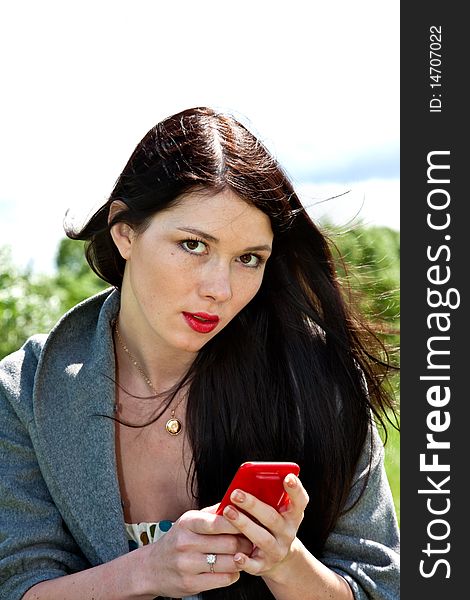 Young cute women with mobile phone in the green park background