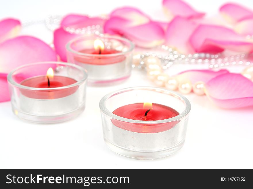 Petals of roses and candles on a white background