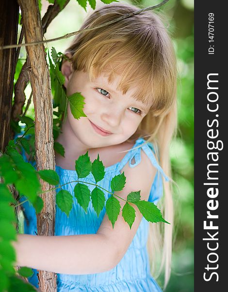 Little girl in blue dress in the park near tree