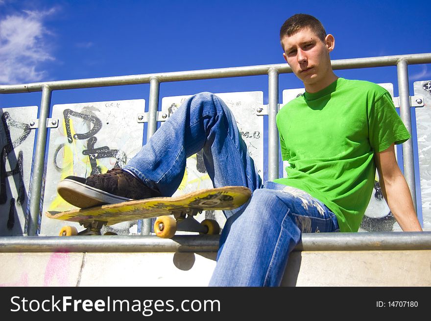 Skateboarder conceptual image. Skateboarder sits in skatepark.