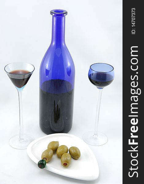 Blue cherry brandy bottle, two glasses and bunch of olives on the plate. Blue cherry brandy bottle, two glasses and bunch of olives on the plate.