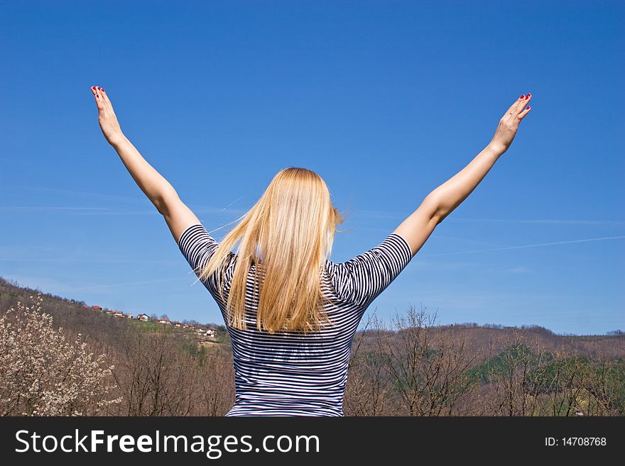 Blond girl posing in nature with sky and hills in background