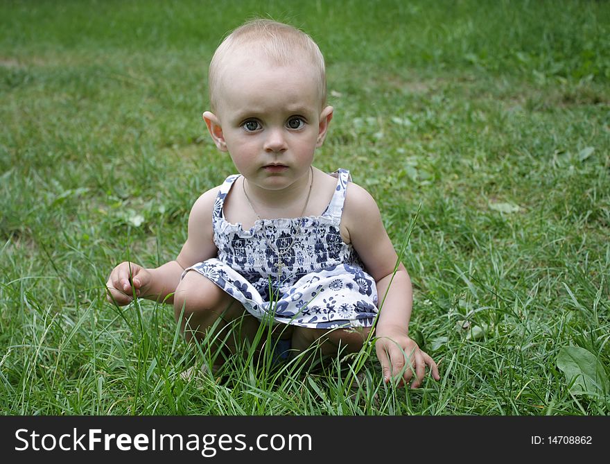 A Little Girl Sitting In The Grass