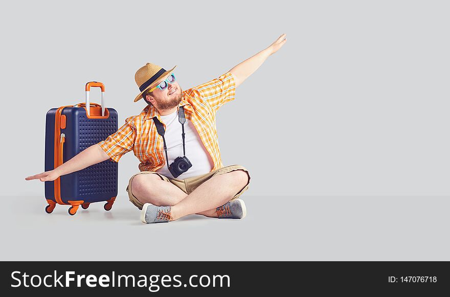 Fat funny man with a suitcase raised his hands up the airplane symbol.