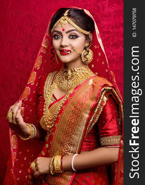 Portrait of young Indian bride wearing gold jewelry and red sari in wedding