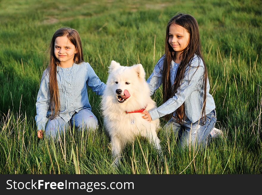 Sisters with a dog on the grass.