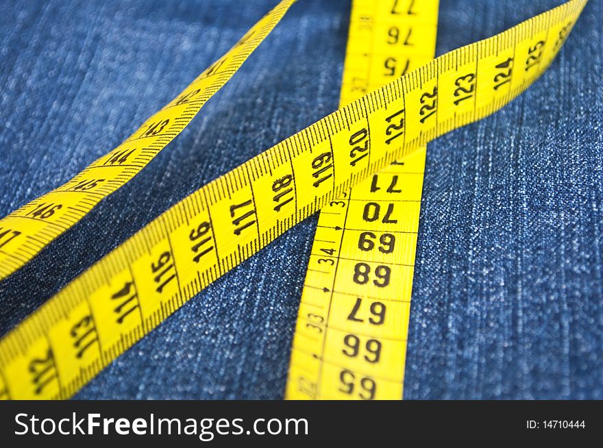Blue jeans and measure tape - concept of overweight