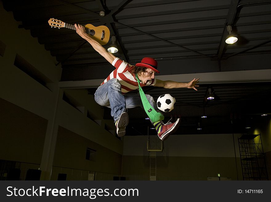 An entertainer flies high holding a guitar while playing soccer. An entertainer flies high holding a guitar while playing soccer