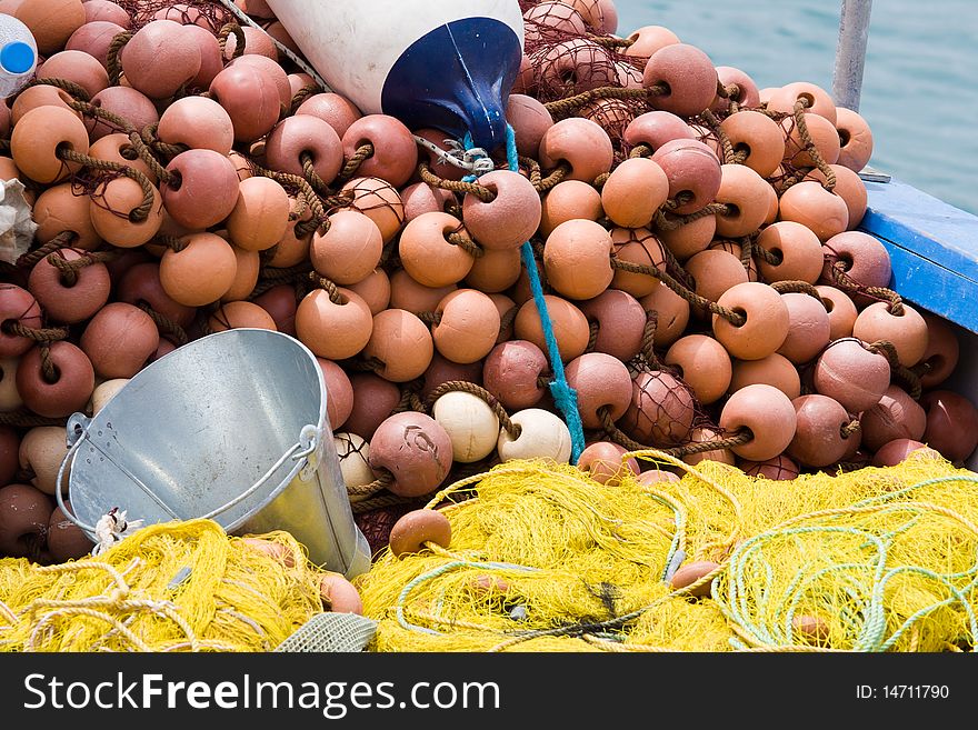 Nylon yellow  fishing net, metal bucket, buoy close-up on the boat desk. Nylon yellow  fishing net, metal bucket, buoy close-up on the boat desk