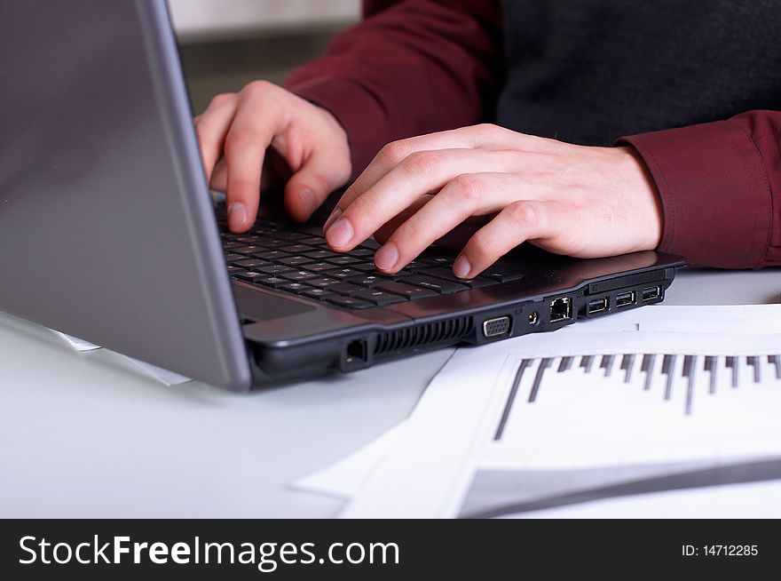 Hands of a young man working on laptop