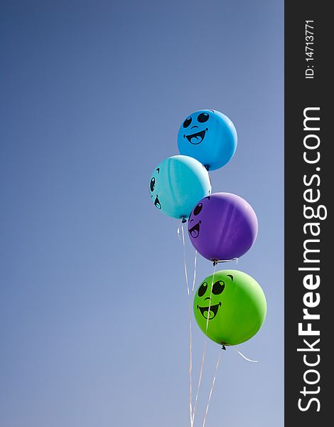 Four happy balloons with smile in cyan sky