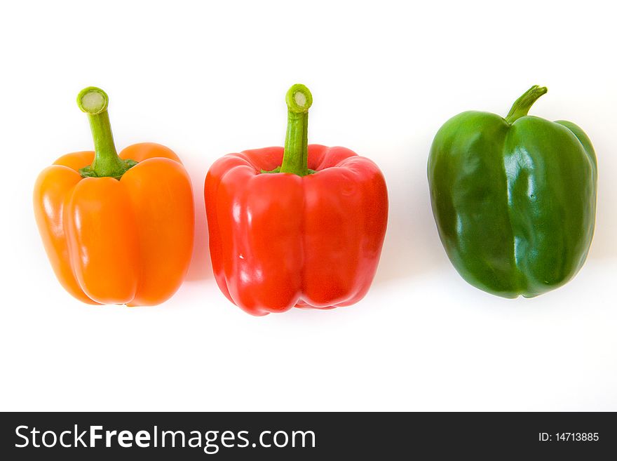 Green, orange and red bell peppers above white. Green, orange and red bell peppers above white