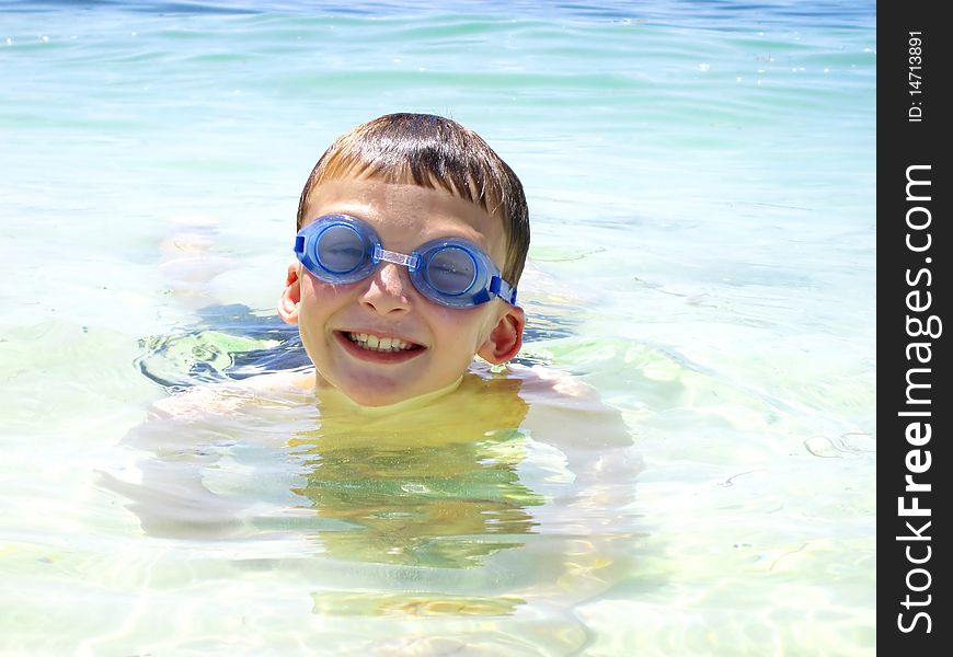 a child swimming in the ocean with goggles. a child swimming in the ocean with goggles