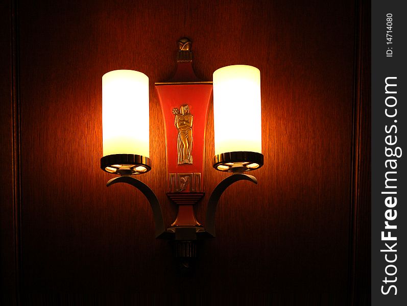 Vintage wall sconce in darkened room, with sculpture