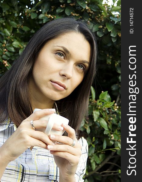Teen girl resting in a park sitting on a bench in the hands of a white cup with coffee. Teen girl resting in a park sitting on a bench in the hands of a white cup with coffee