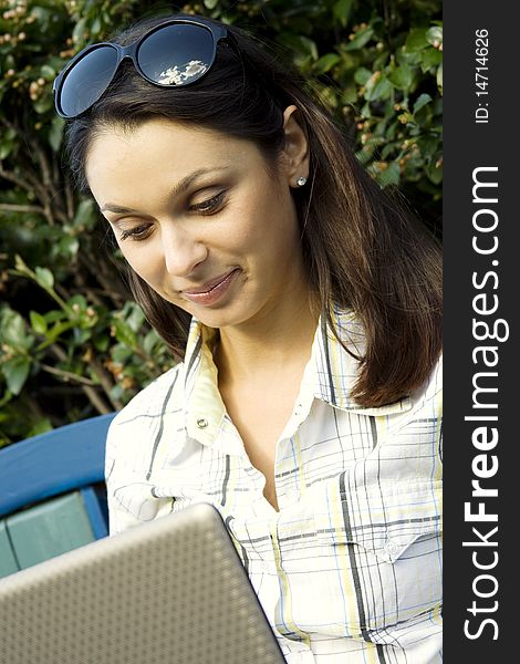 Young woman sits on a wooden park bench with laptop. Young woman sits on a wooden park bench with laptop