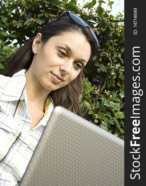 Young woman sits on a wooden park bench with laptop. Young woman sits on a wooden park bench with laptop