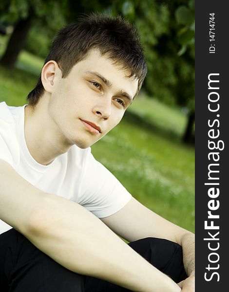 Teenager in a park in a white shirt against the green leaves of the tree. Teenager in a park in a white shirt against the green leaves of the tree