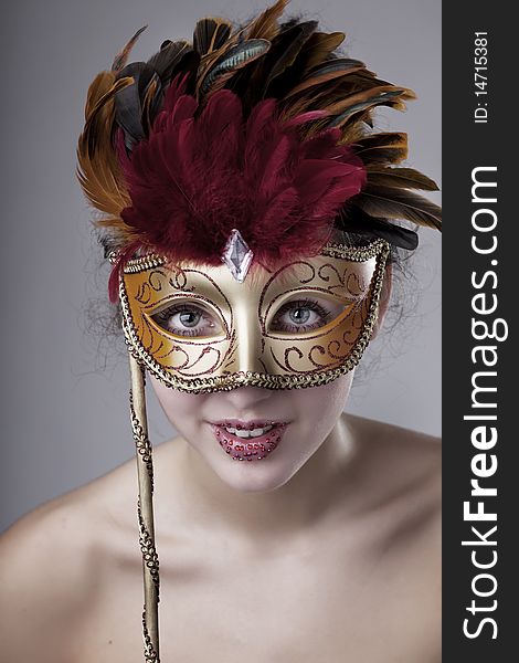 The image of a beautiful girl with a carnival mask in the hands