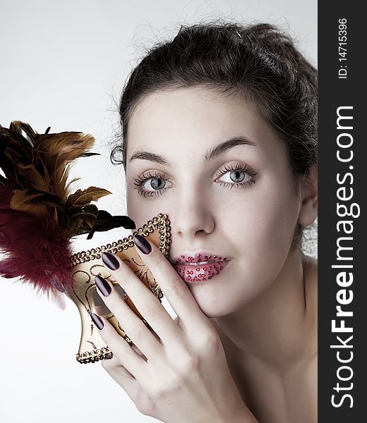 The image of a beautiful girl with a carnival mask in the hands