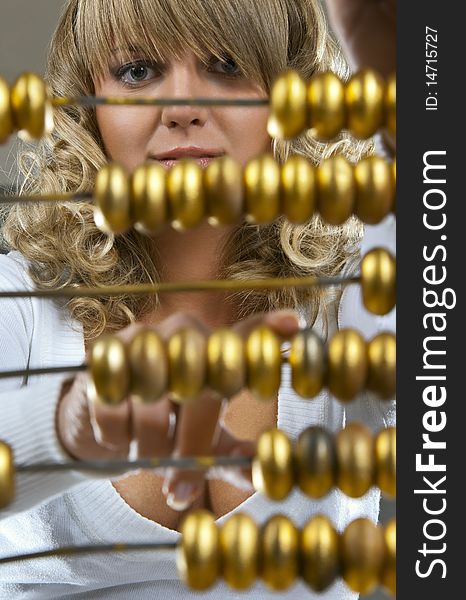 Charming girl looking through and calculating with a golden abacus. Charming girl looking through and calculating with a golden abacus