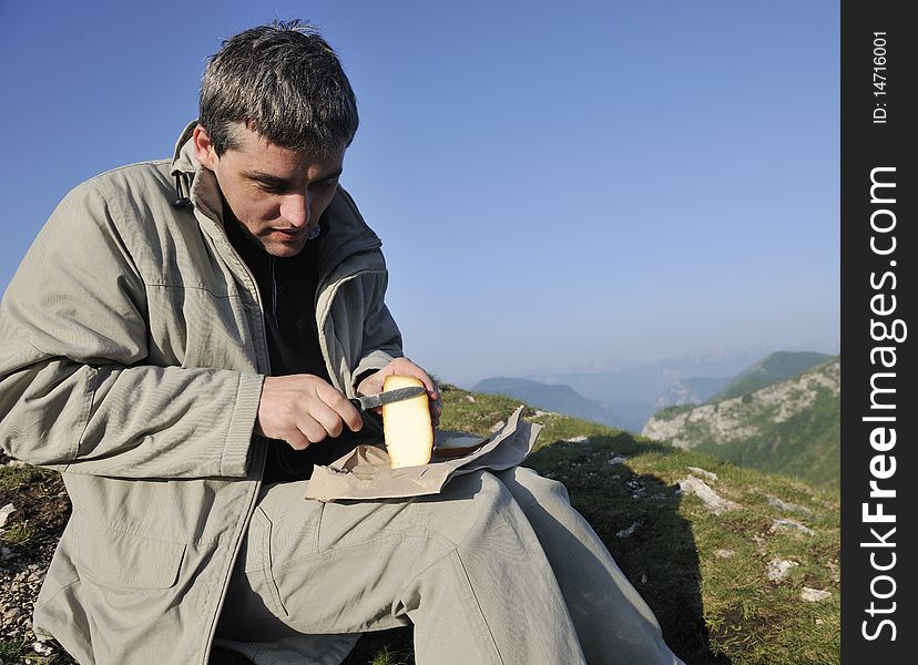 Young happy, man slice fresh milk product cheese outdoor in nature. Young happy, man slice fresh milk product cheese outdoor in nature