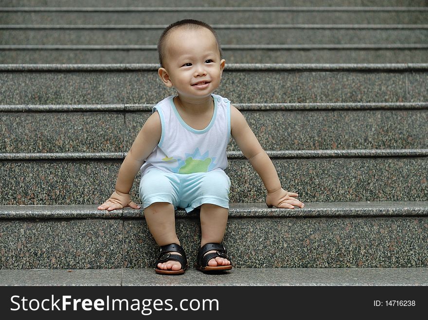 It is a cute happy chinese baby. He is sitting on the stair. It is a cute happy chinese baby. He is sitting on the stair.