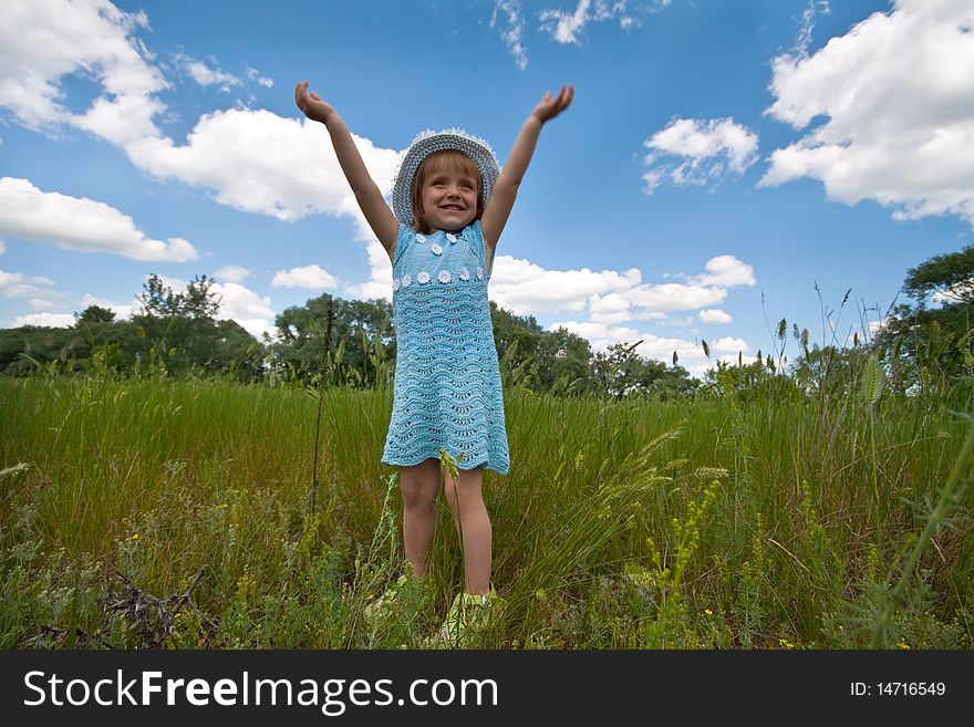 Cute little girl rising hands in a grass field. Cute little girl rising hands in a grass field