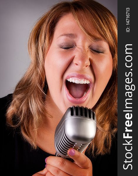 A beautiful young redheaded woman sings a song into an old fashion microphone. A beautiful young redheaded woman sings a song into an old fashion microphone.