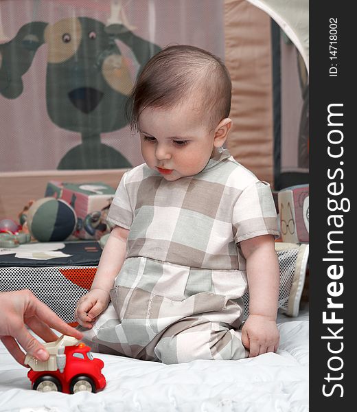 Year-old boy sitting on his knees and looks at a toy car. Year-old boy sitting on his knees and looks at a toy car