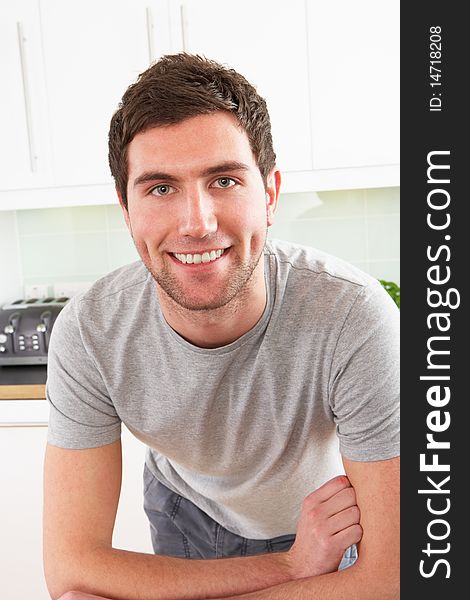 Young Man Relaxing In Modern Kitchen Smiling At Camera