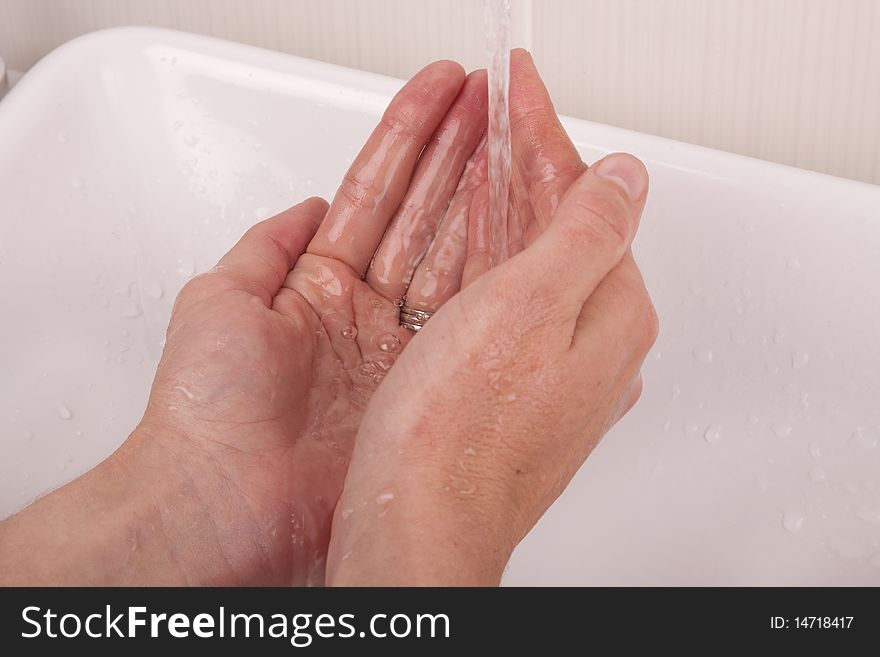 Two hands under a runny tap, washing hands with water