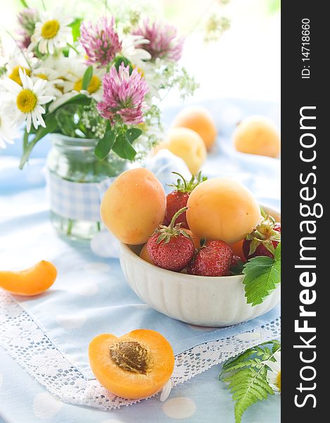 Fresh apricots and strawberries in and beside bowl