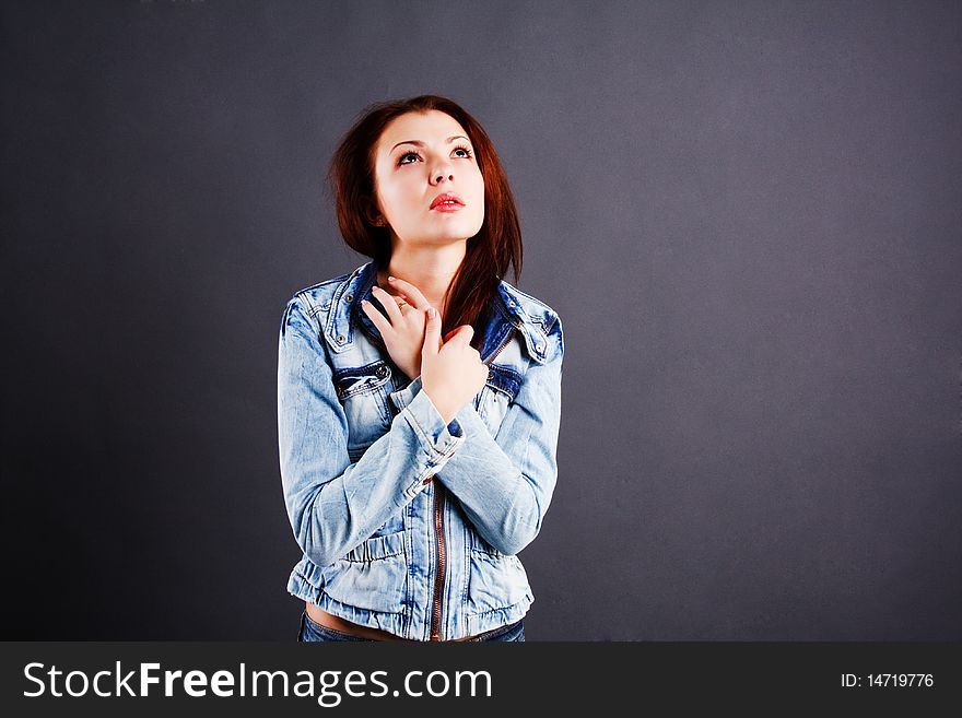 Picture of a young beautiful girl in denim jacket on grey background