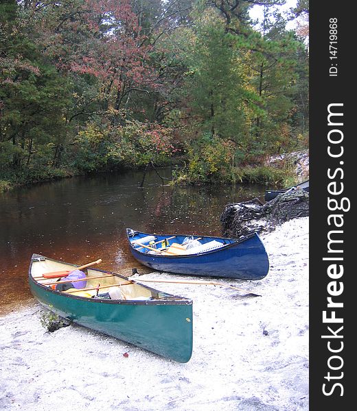 A blue and green canoe sit on river bank waiting to complete the journey. A blue and green canoe sit on river bank waiting to complete the journey